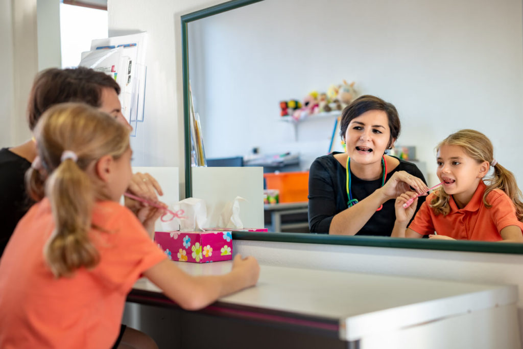 Speech-language professional working with a child during a therapy activity